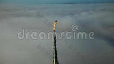 在圣米歇尔山顶上的<strong>金色</strong>圣米迦勒雕像周围飞行，塔尖在云层上方的<strong>阳光下</strong>发光